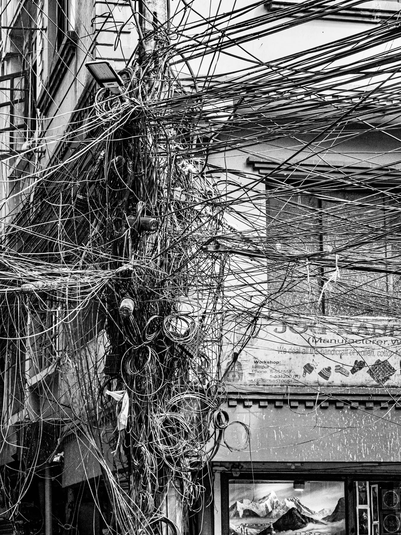 A cluster of tangled wires attached to a utility pole, set against a dim sky, symbolizing frayed connection