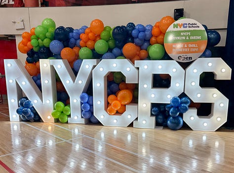 Professional people at a small business expo and the letters NYCPS surrounded by balloons