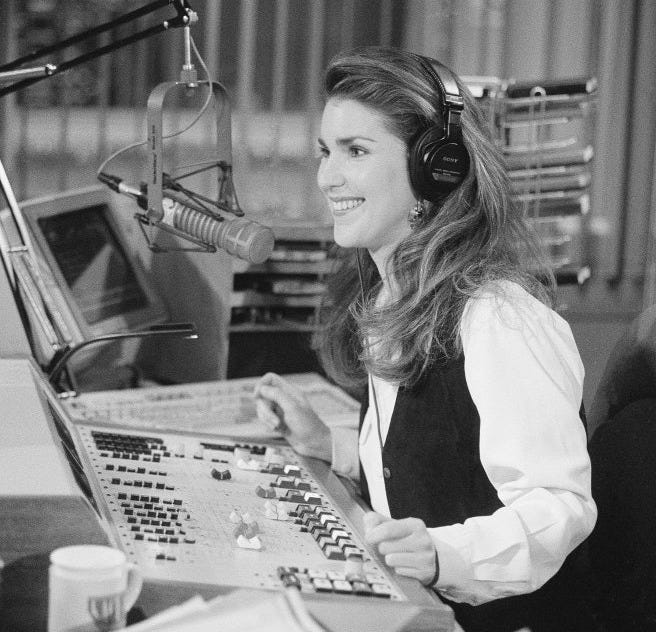 This may contain: a woman sitting in front of a microphone with headphones on and looking at the screen
