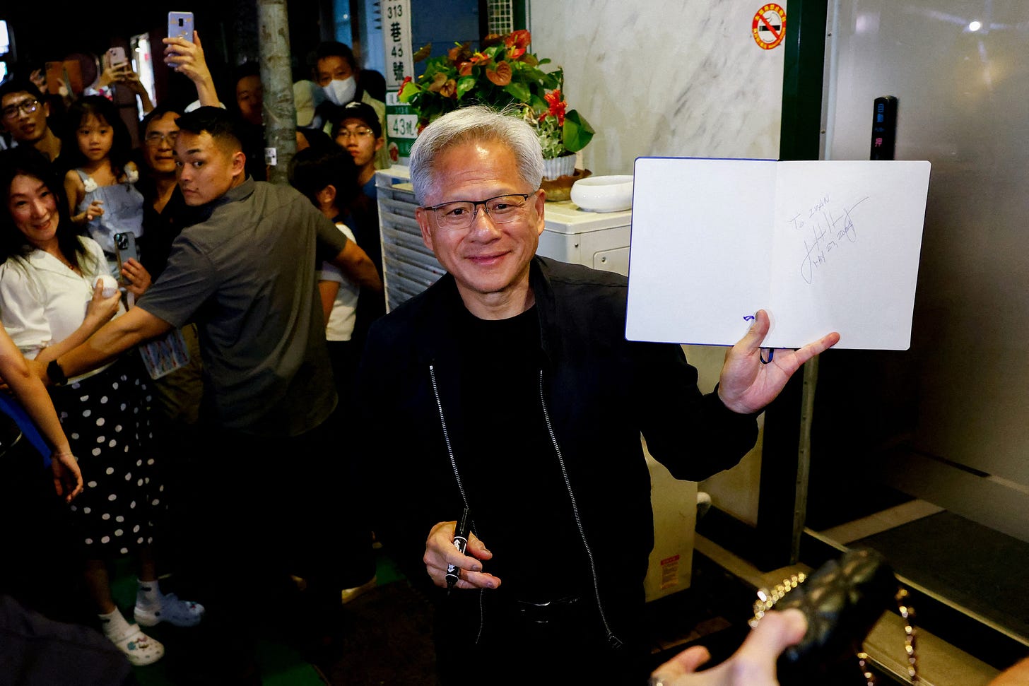 Nvidia's (NVDA.O) CEO Jensen Huang interacts with the media and supporters outside a restaurant in Taipei