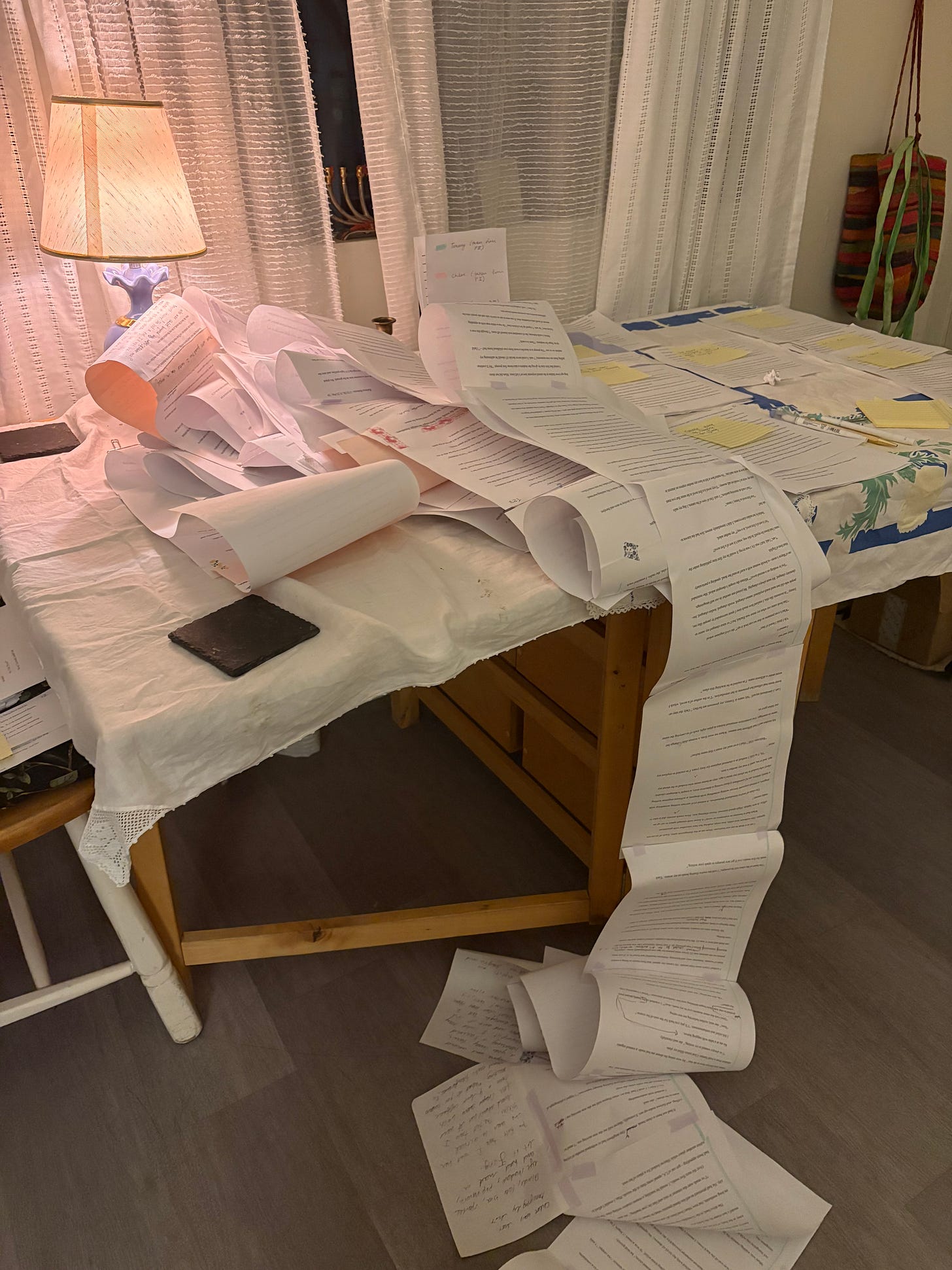 A long scroll of paper spilling off a dining room table. In the window, a menorah.