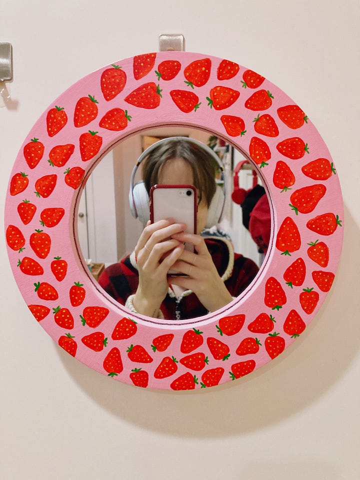 One mirror has stacks of donuts around the frame and the other is pink with strawberries painted all around the frame.