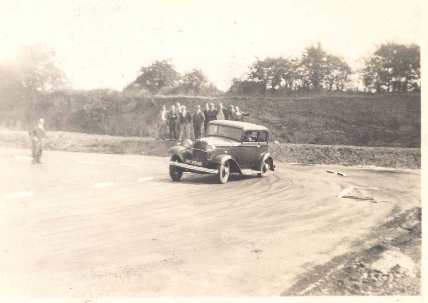 A car careens round the skid pan whilst other officers observe.