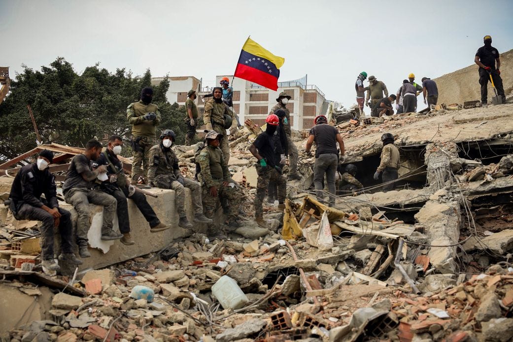 Rescuers search for victims at a collapsed building as one raises a Venezuelan flag following powerful earthquakes that struck Venezuela on June 28, 2026 in Caraballeda, La Guaira, Venezuela. Rescuers search for victims at a collapsed building as one raises a Venezuelan flag following powerful earthquakes that struck Venezuela on June 28, 2026 in Caraballeda, La Guaira, Venezuela.