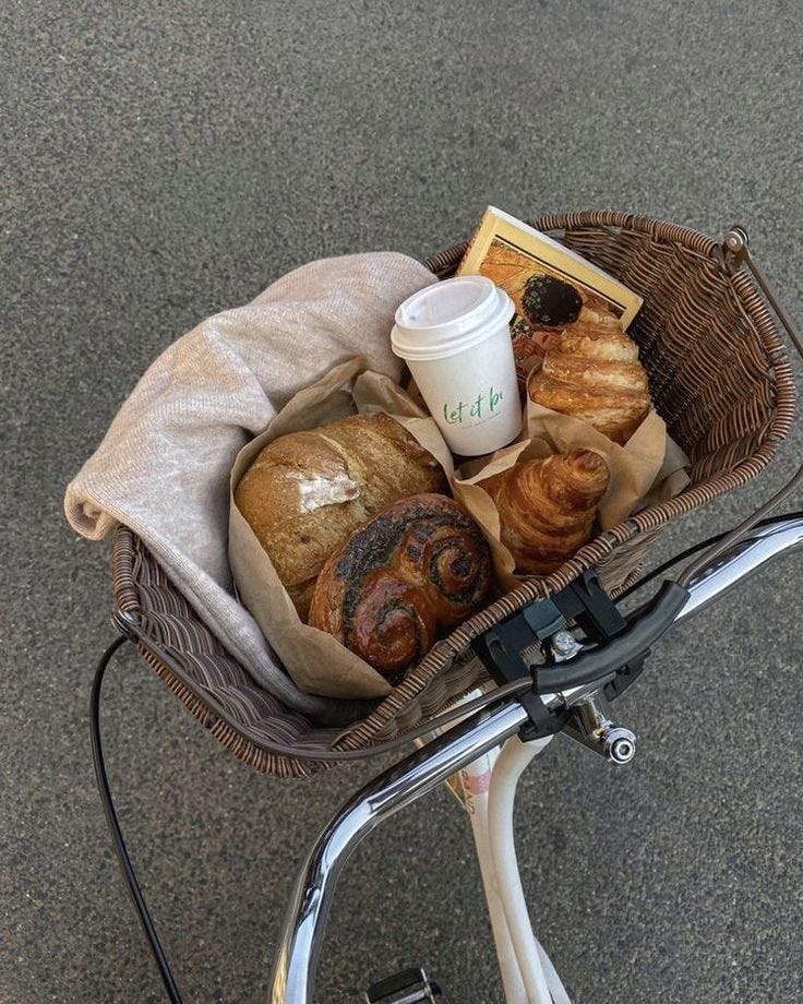 This may contain: a basket filled with bread and croissants on top of a bike