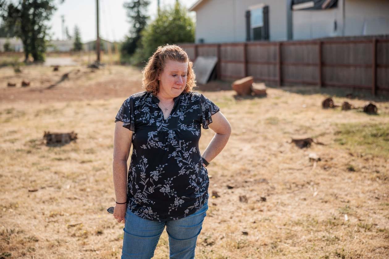 Woman standing on the site of her former home, destroyed in the 2018 Camp Fire.