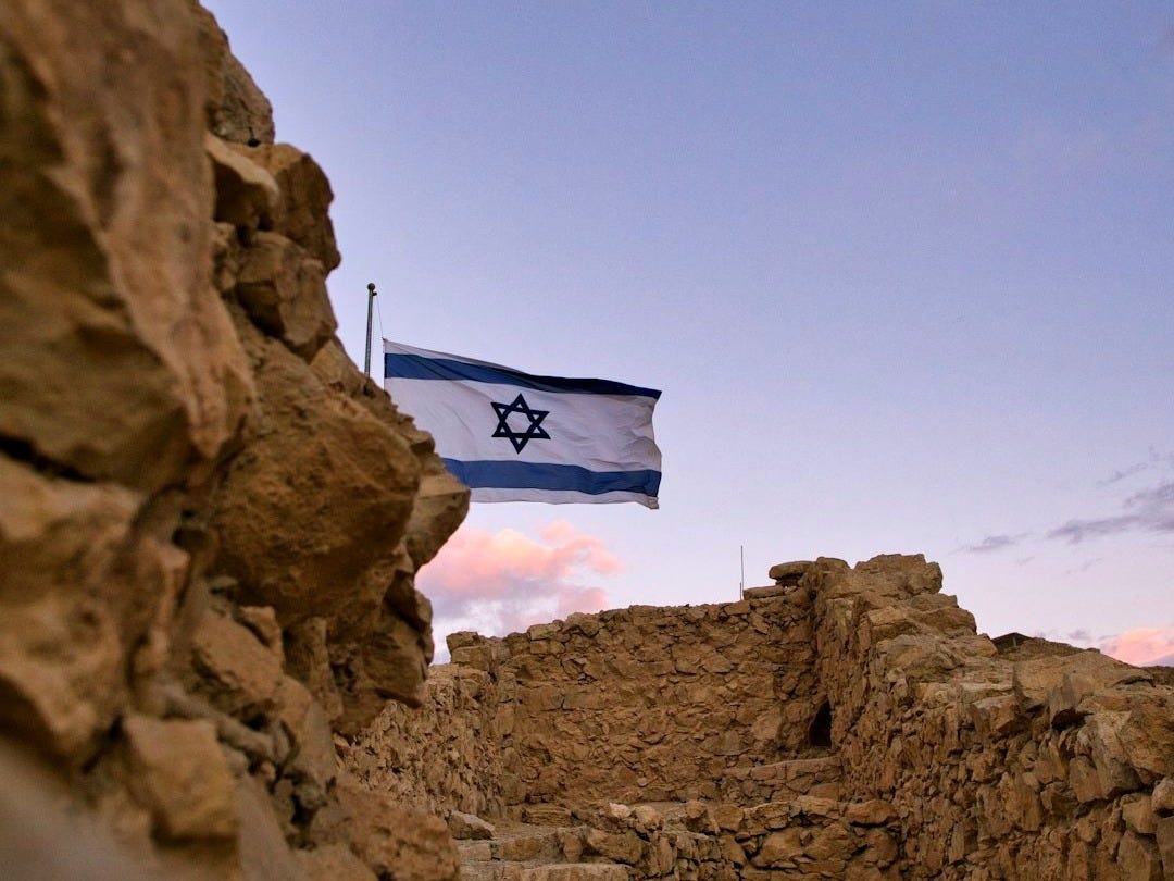 an israeli flag flying over a rocky area an israeli flag flying over a rocky area