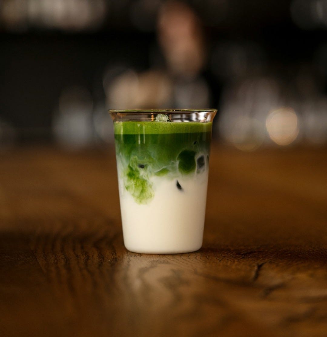 a shot glass filled with green liquid on top of a wooden table a shot glass filled with green liquid on top of a wooden table