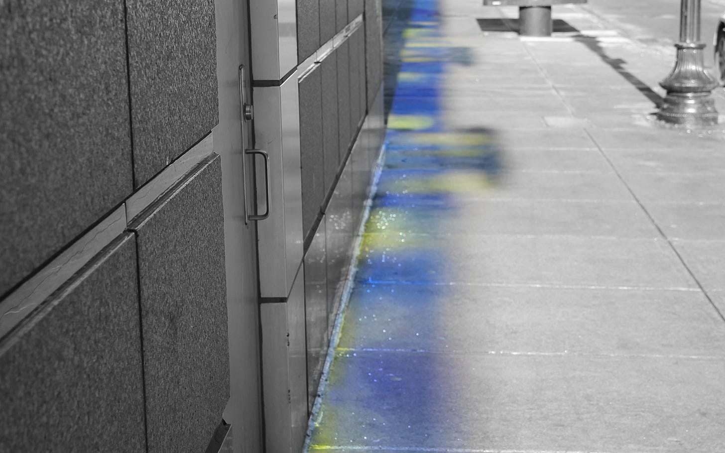 Black and white photo of a city street with a blue and yellow spectrum cast from windows onto the sidewalk. Black and white photo of a city street with a blue and yellow spectrum cast from windows onto the sidewalk.