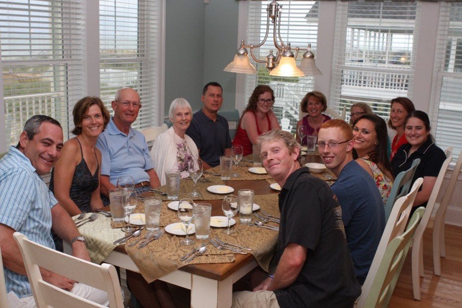 Large family gathered around a dinner table, representing a friends-and-family round conversation.