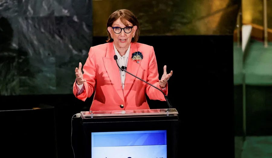 Rebeca Grynspan hablando desde un atril, vestida con una chaqueta coral y gesticulando con ambas manos. 