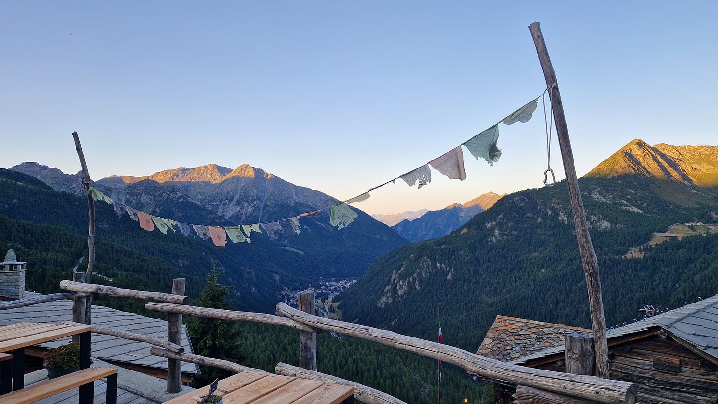 Prayer flags flying on a line above a wooden balcony. Mountain on horizon. Prayer flags flying on a line above a wooden balcony. Mountain on horizon.