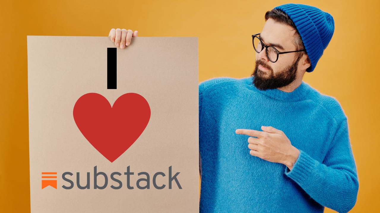 A man wearing a blue sweater and beanie holding a sign that says, "I Love Substack."