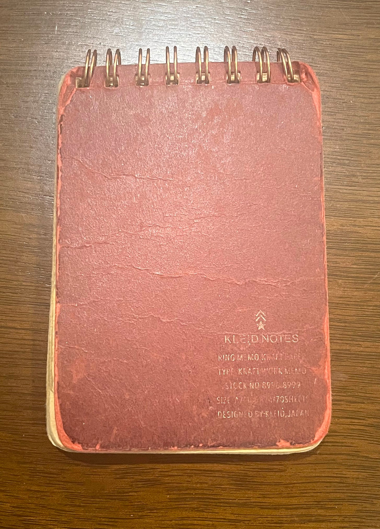 A small, red, spiral-bound notebook that's beat up and frayed at the edges.