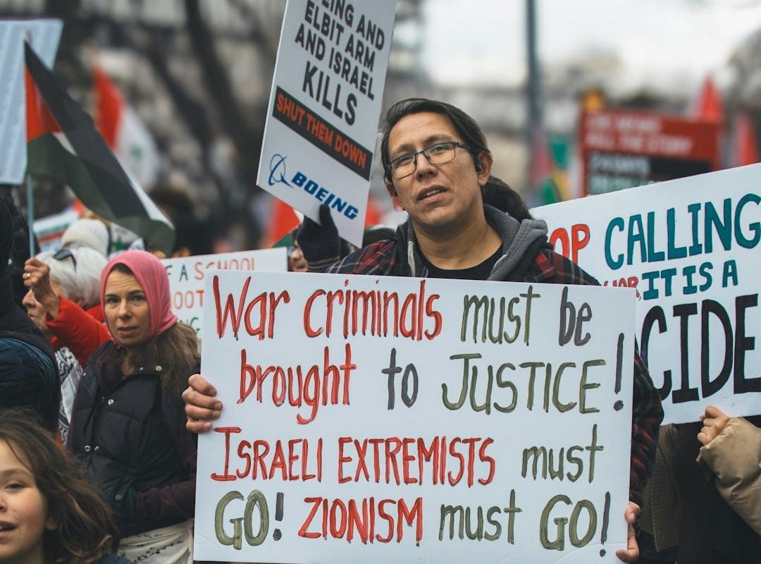 a man holding a sign in front of a crowd of people a man holding a sign in front of a crowd of people