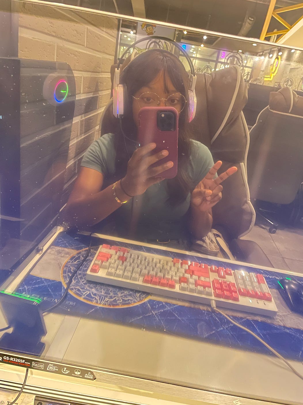 A selfie of Kat at a gaming cafe in South Korea. She is sitting in front of a fancy gaming keyword and wearing a glowing gaming headset. A selfie of Kat at a gaming cafe in South Korea. She is sitting in front of a fancy gaming keyword and wearing a glowing gaming headset.