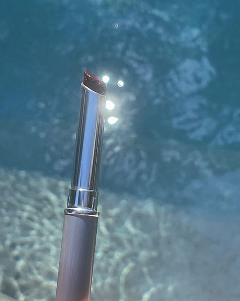 "Product shot of Clinique Black Honey lipstick, placed against a poolside background to highlight the aesthetic appeal of the cult-favorite makeup item.