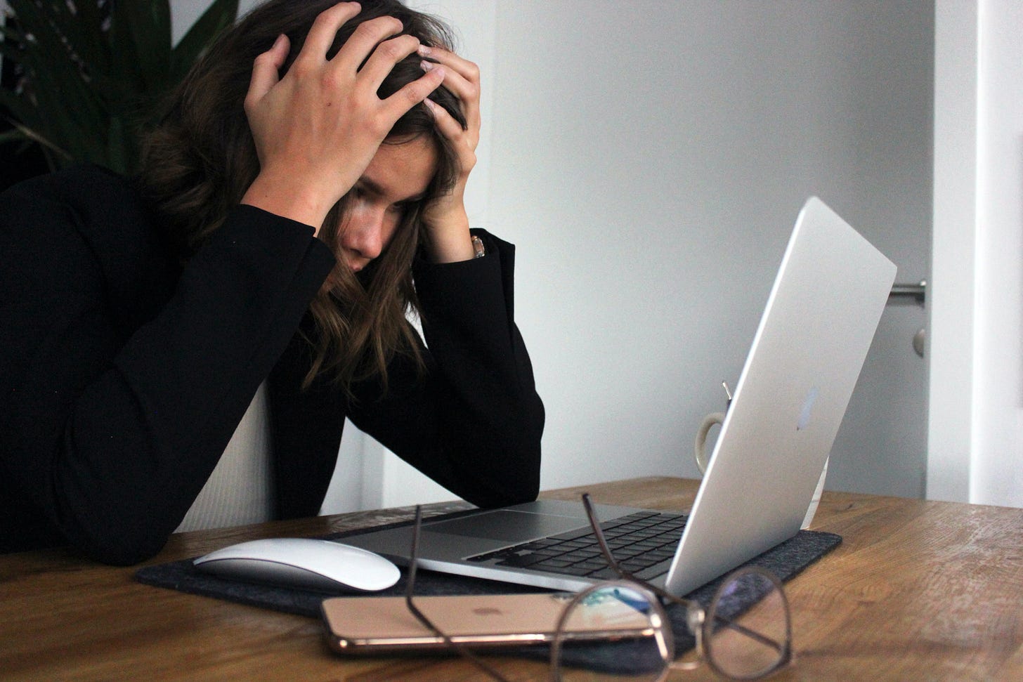 Woman looking at a laptop with her hands on her head indicating that she is stressed or is at a loss Woman looking at a laptop with her hands on her head indicating that she is stressed or is at a loss