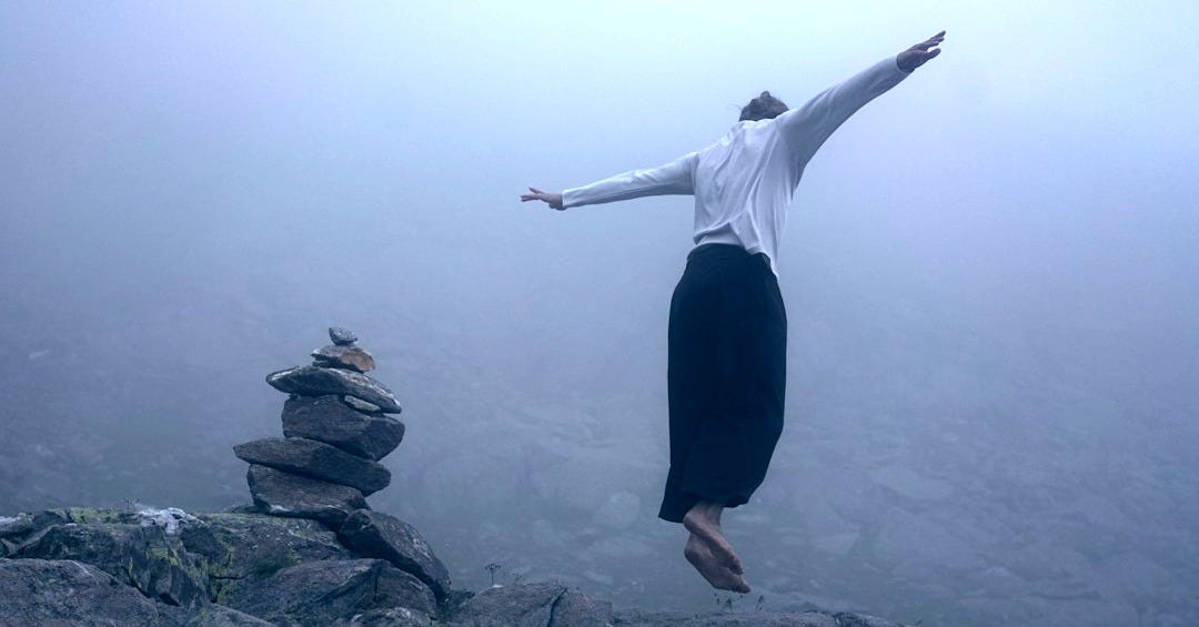 woman in white long sleeve shirt and black pants standing on rock