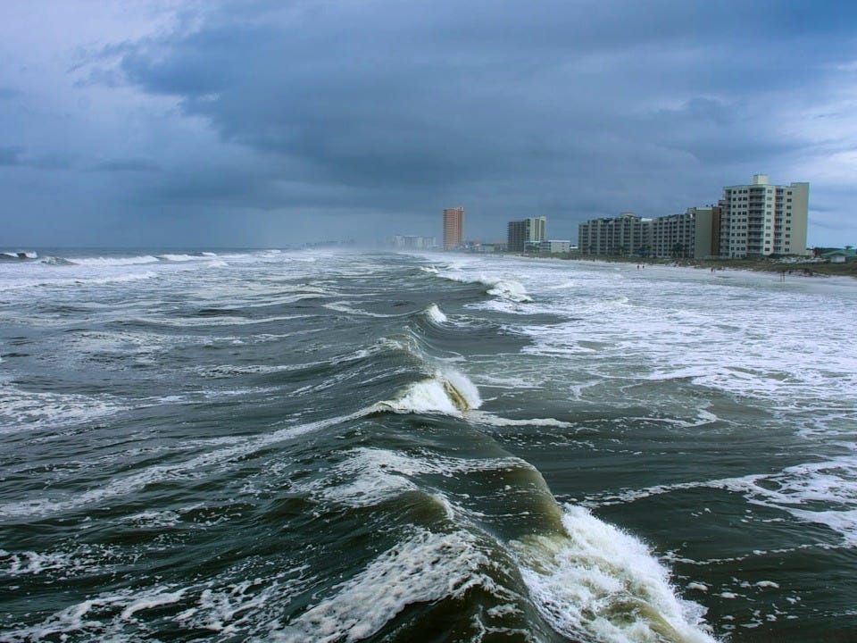 ocean waves near city buildings during daytime