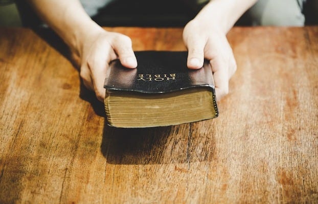 Spirituality and religion, Hands folded in prayer on a Holy Bible in church concept for faith.