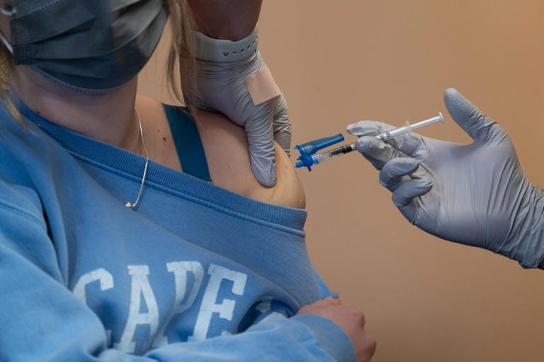 A healthcare worker administers a dose of the Pfizer-BioNTech Covid-19 vaccine at a vaccination clinic in the Peabody Institute Library in Peabody, Massachusetts, U.S., on Wednesday, Jan. 26, 2022. The state's Covid-19 numbers are improving to the point Massachusetts residents, especially those who are fully vaccinated and boosted, could see significantly lower risk from the coronavirus, according to Tufts Medical Center.