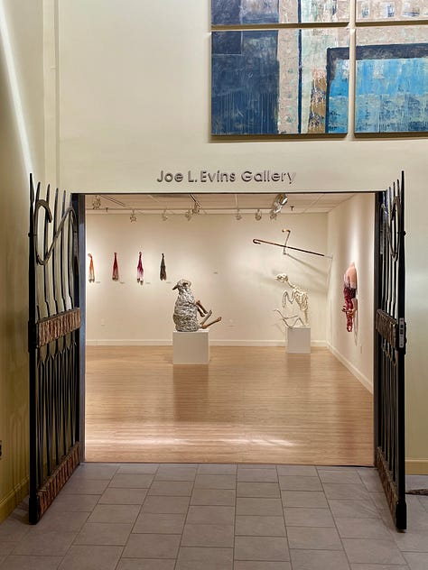 Installation views of a gallery with several artworks depicting sheep. All works are made of ceramic with fiber attachments connecting them together.
