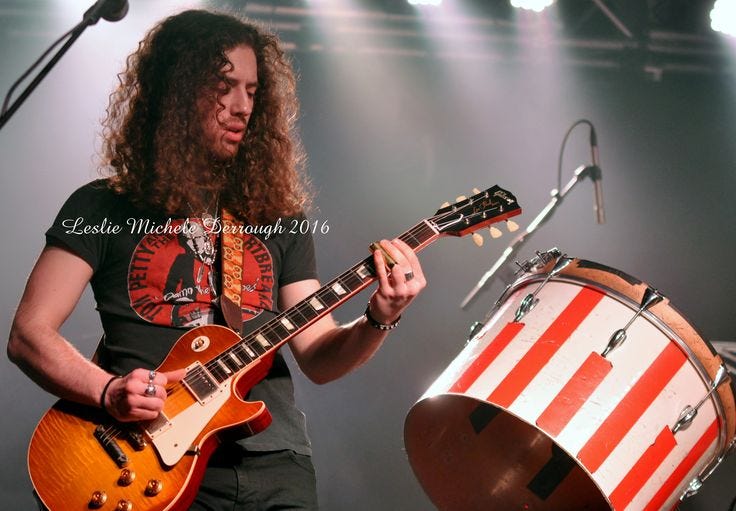 This may contain: a man playing an electric guitar on stage This may contain: a man playing an electric guitar on stage
