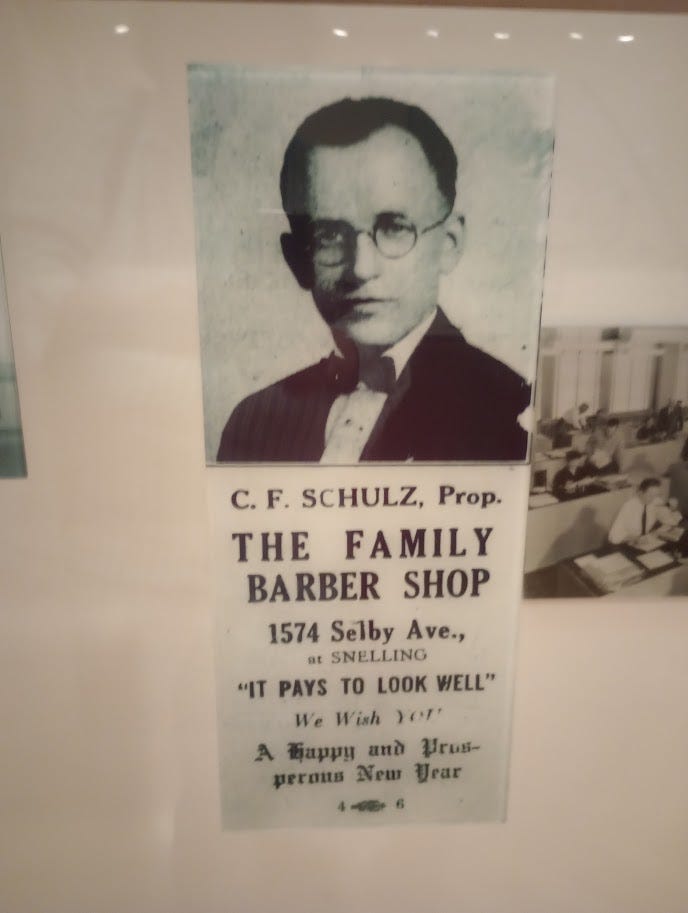 Newspaper ad for Charles F. Schulz's barbershop, and cartoon of Charlie Brown with barber pole and sign saying Family Barber Shop