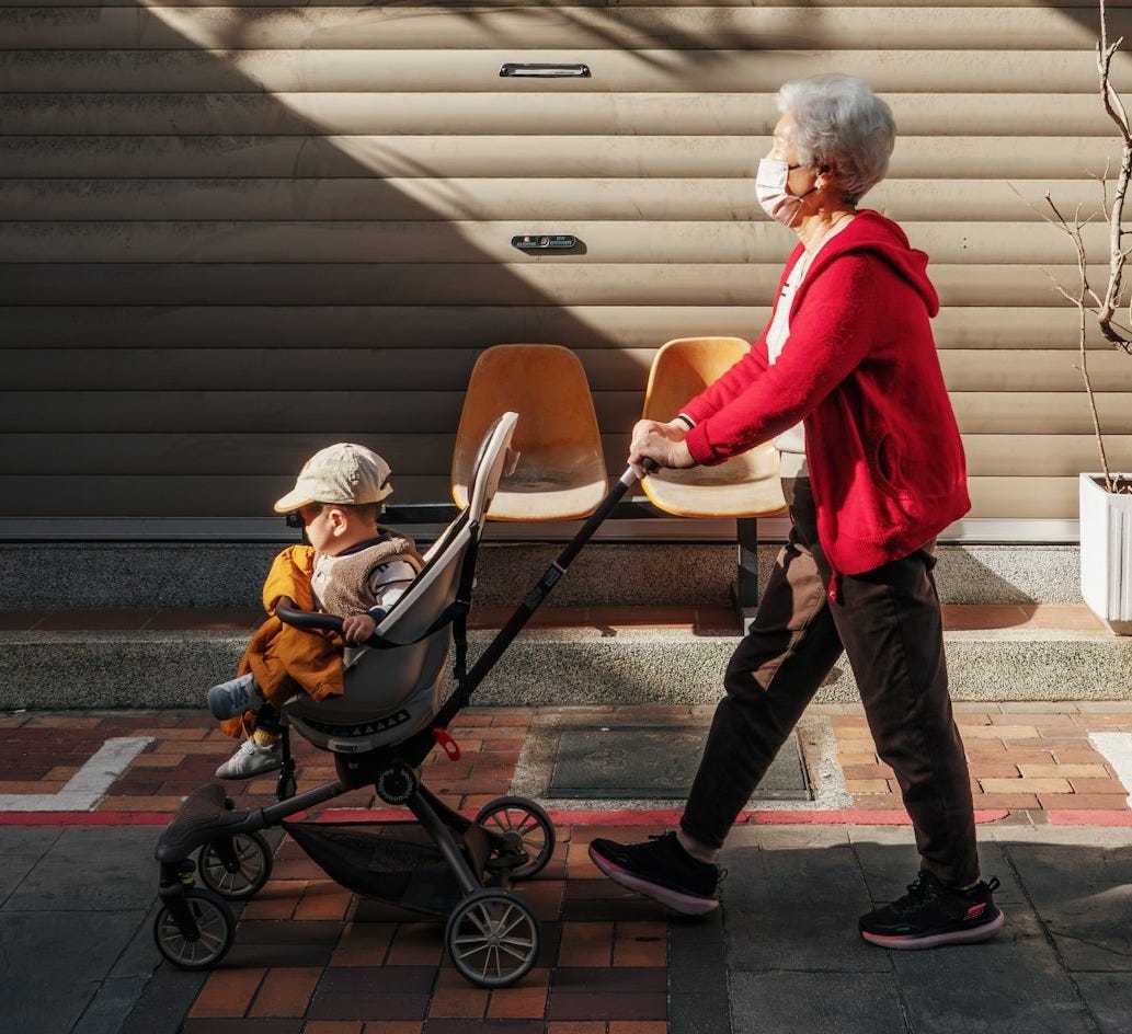 Elderly person with mask pushes child in stroller