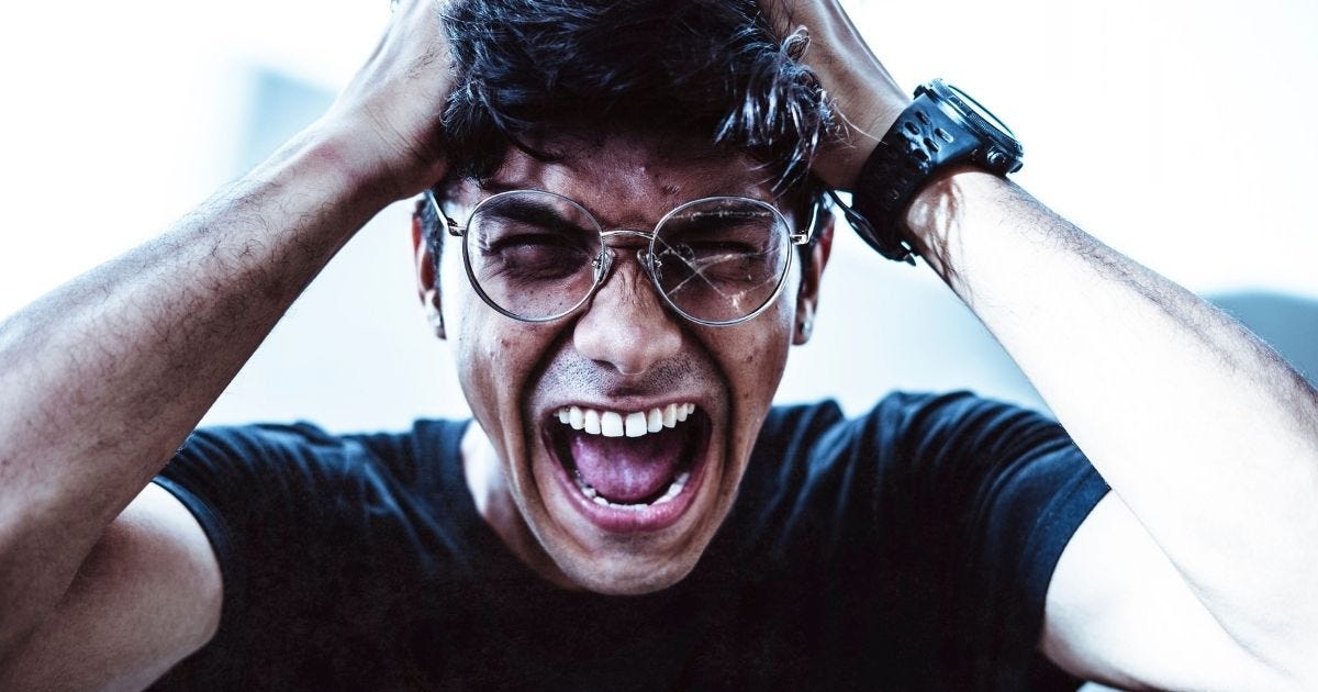 A close-up of a man shouting in frustration, clutching his head with broken eyeglasses on A close-up of a man shouting in frustration, clutching his head with broken eyeglasses on