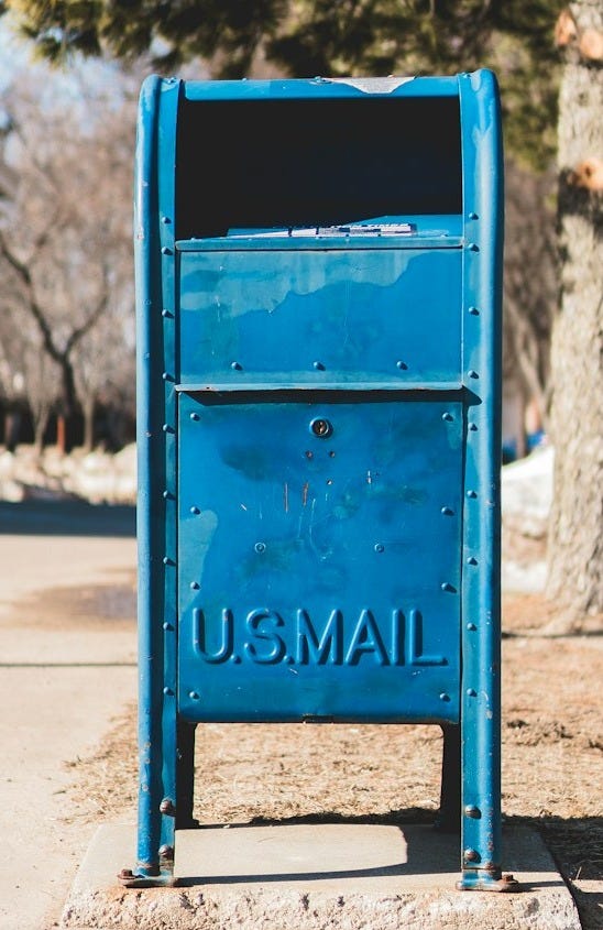 blue U.S. mail box on concrete pavement