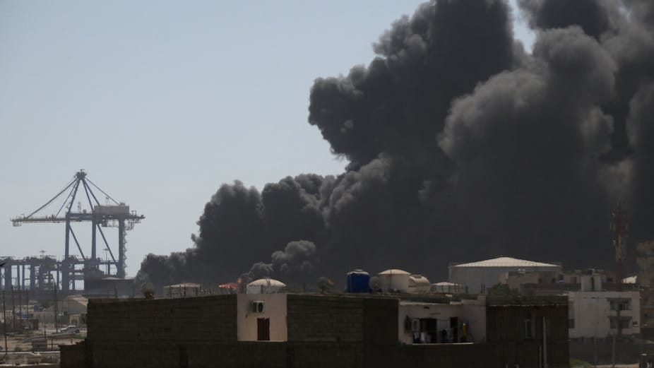 A large plume of black smoke rising, with a crane in the background