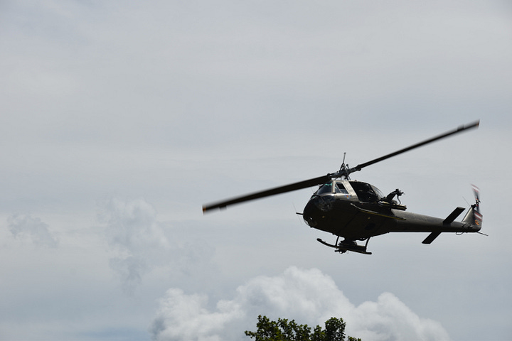 Two photos of Huey helicopters in flight with cloudy skies above.