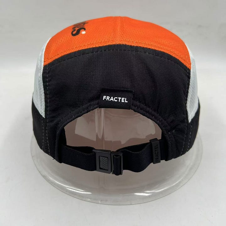Images of the Footnotes Fractel hat including the orange logo on the front panel and underneath the brim. The newsletter's name is typed on the top of the hat and a green stripe accents the brim.