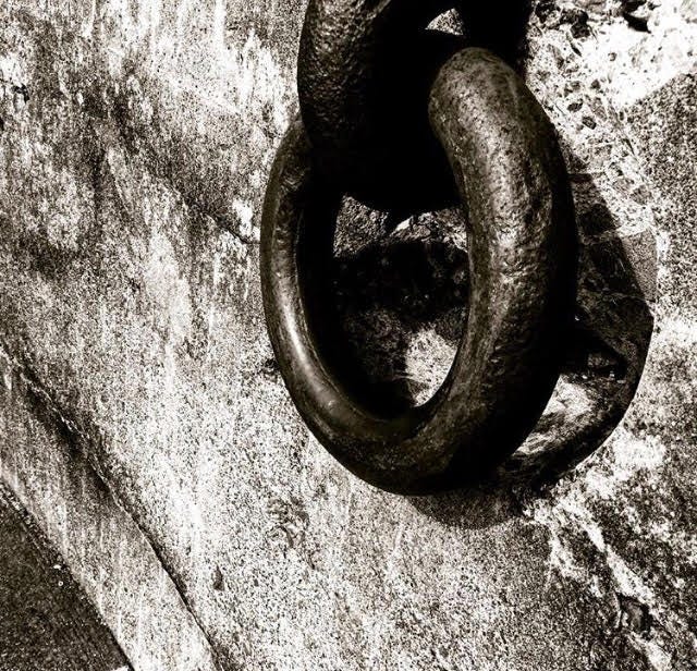 A black and white photo of chain links on a wall.