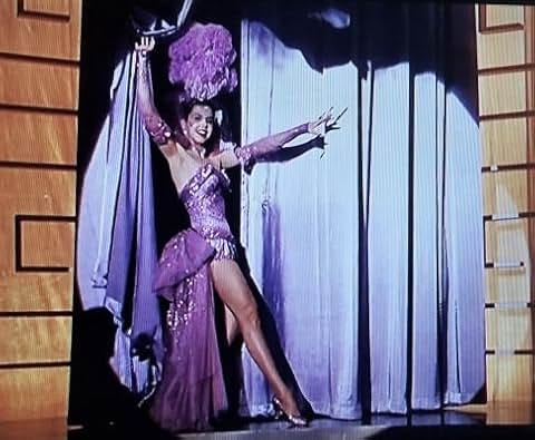 Ann Miller playing Bubbles in Lovely to Look At. She is wearing a purple sequinned leotard style dancing costume with matching gloves, headdress and skirt. 