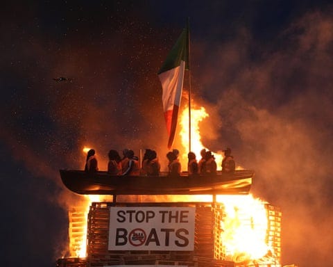 Flames engulf the representation of a refugee vessel