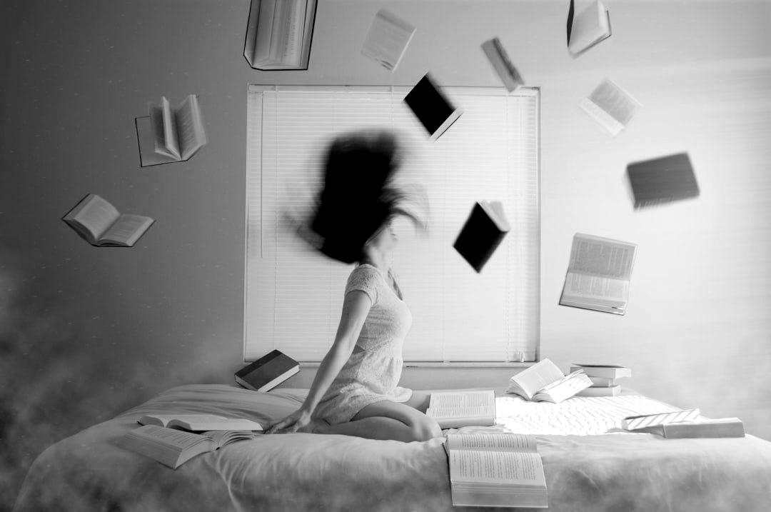 woman sitting on bed with flying books