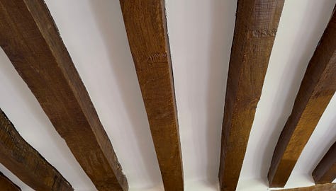Left: the original wooden ceiling beams of the château living room. Middle: copper pots and pans on the floor catching water leaking from the ceiling. Right: a wastebasket on a stained sofa during the plumbing leak.