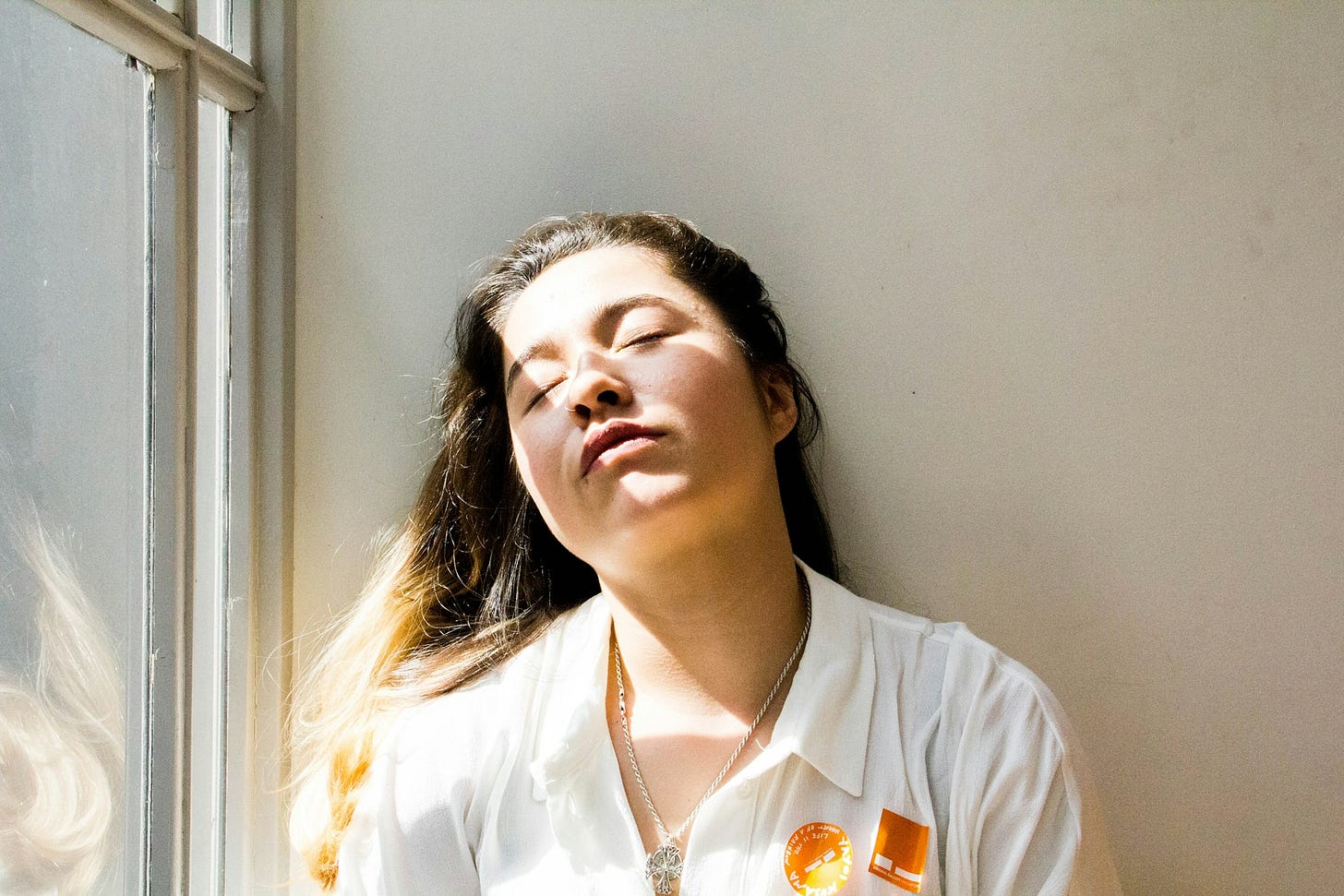 Woman with closed eyes in bright sunlight, representing emotional overwhelm when the body shuts down