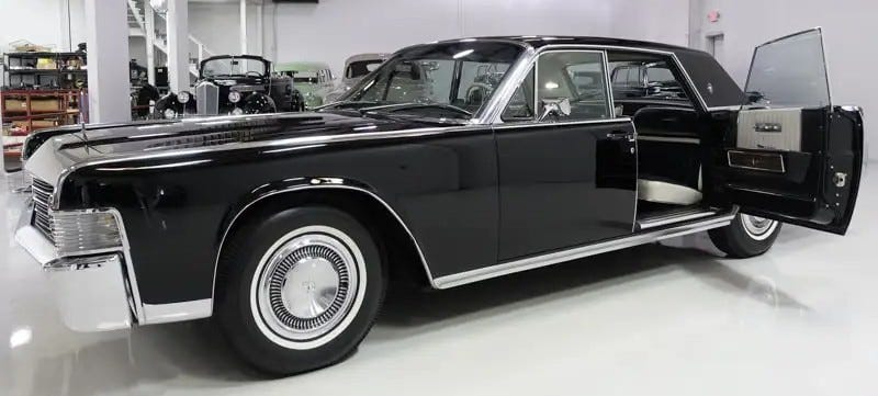 Black 1965 Lincoln Continental with left rear suicide door open