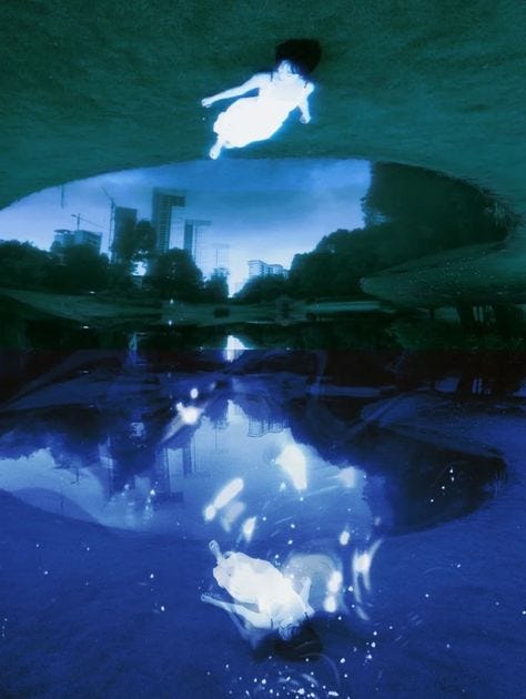 This may contain: the reflection of a person diving in water