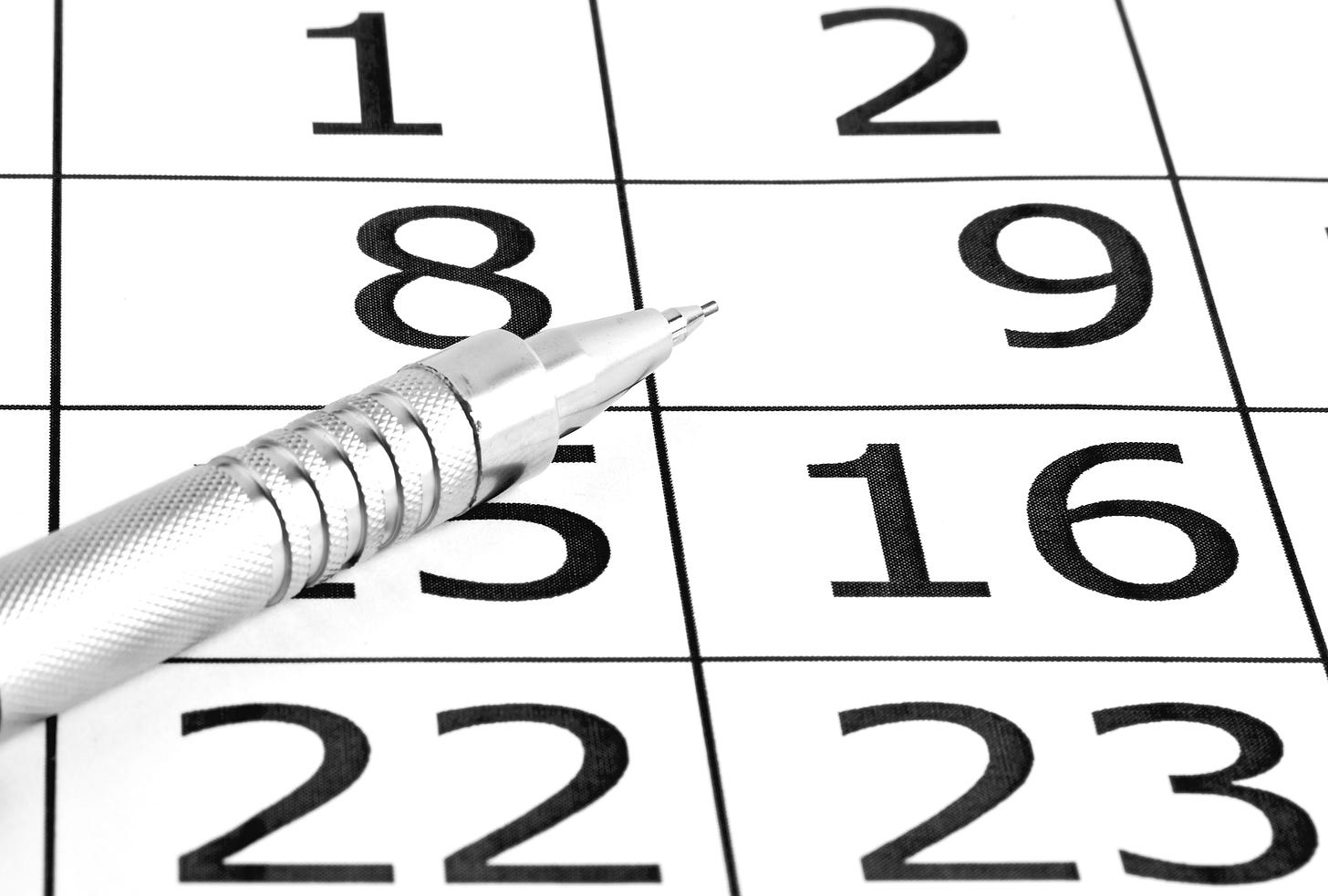 Close-up of a pen on a calendar representing a quarterly planning cycle.