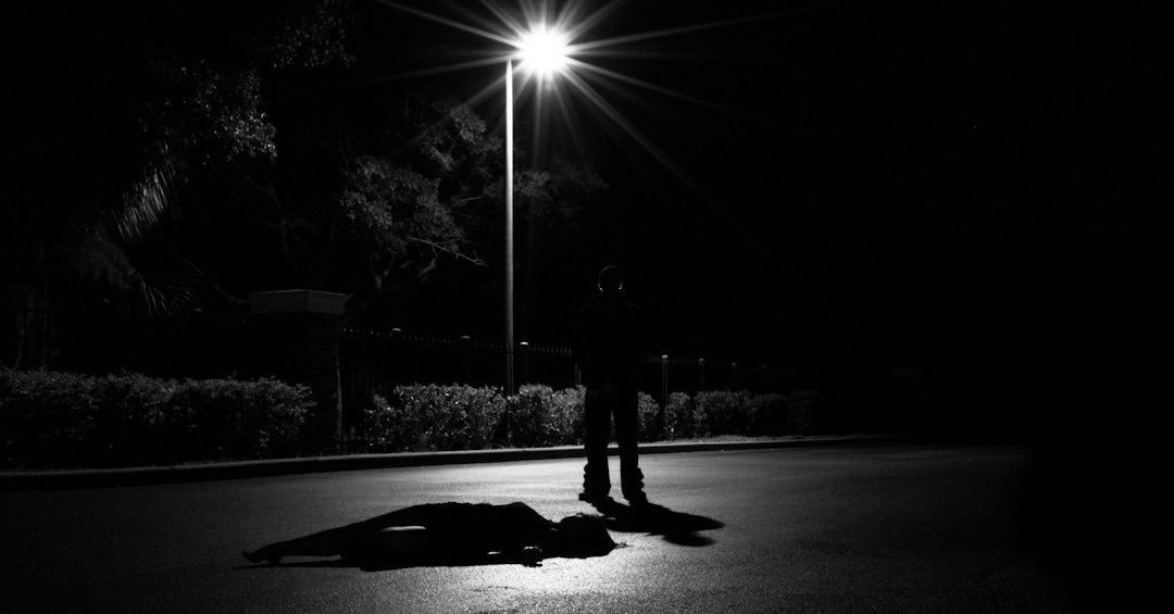 a person laying on the ground under a street light a person laying on the ground under a street light