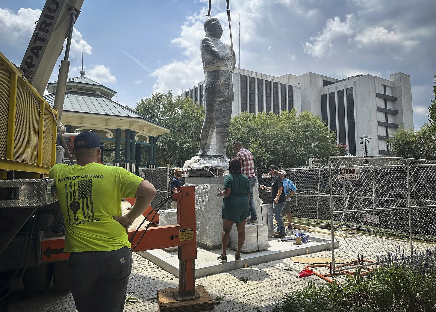 A group of people working on a statue

Description automatically generated