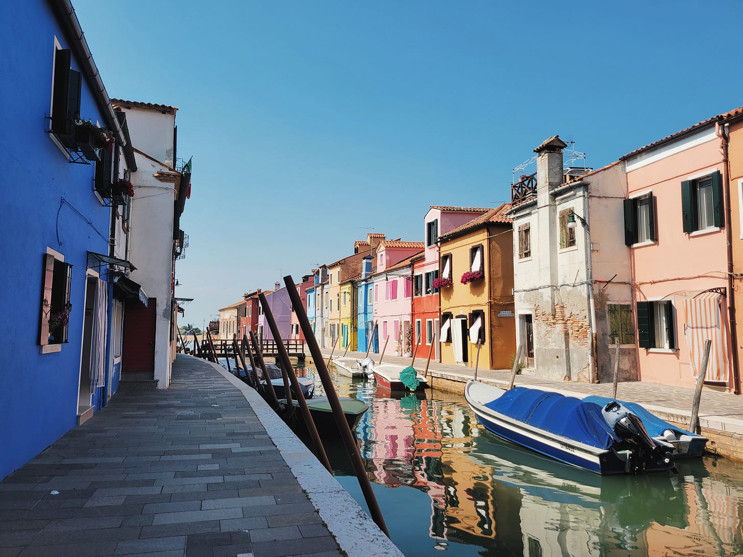 Brightly painted houses reflected in a canal on the island of Burano Brightly painted houses reflected in a canal on the island of Burano
