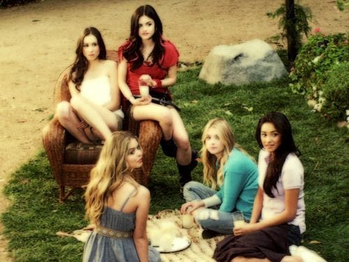 This may contain: four beautiful women sitting on top of a grass covered field next to eachother