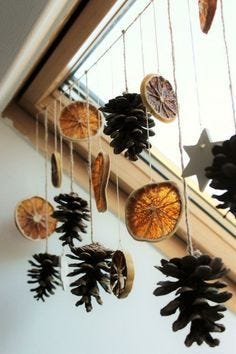 This may contain: some pine cones hanging from a window sill next to a star and tree branch This may contain: some pine cones hanging from a window sill next to a star and tree branch