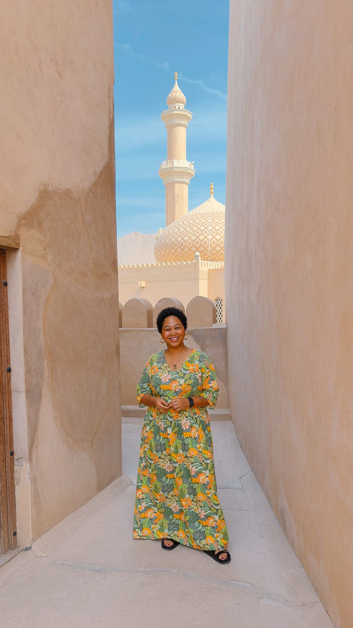 four photos, including: a plate of prawns with mini paratha, Anela standing in front of a mosque with tan stone walls around her, an ornate huge lamp with filigree and light shining through, and a plate of Shuwa, a common dish in Oman of marinated meat that has been cooked underground and served with rice.